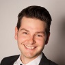 Smiling young man with black hair and suit