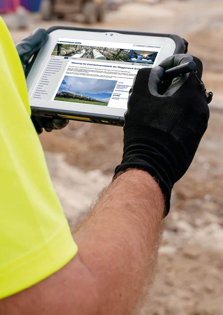 Site engineer surveyor using rugged tablet controller computer to operate EDM total station for setting out and surveying close-up