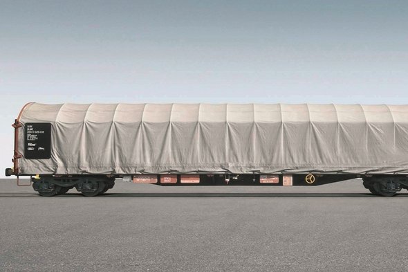 Flat car with white tarpaulin on gray background.