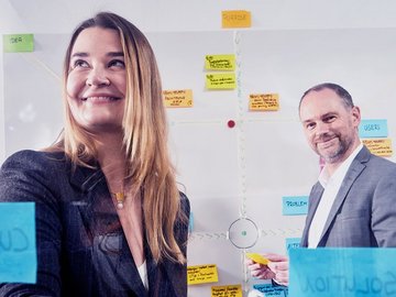 Woman and man stand in front of many sticky notes.