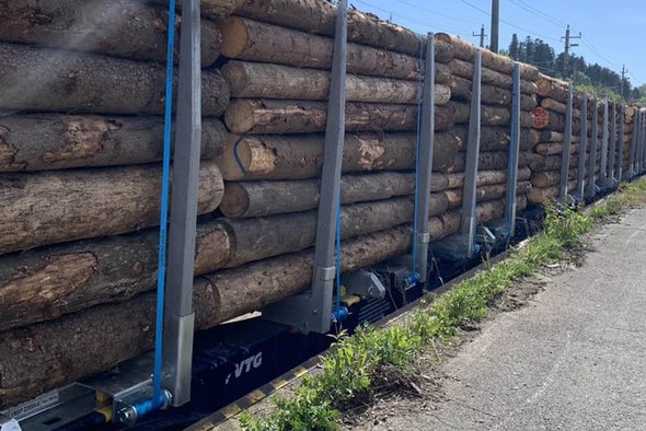 Blue modular structure with sawn logs stacked on top of each other.