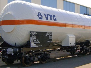 White liquid gas tank car with orange stripe and blue logo.