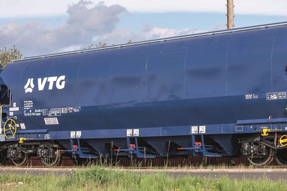 Blue hopper car with white VTG logo against green background.