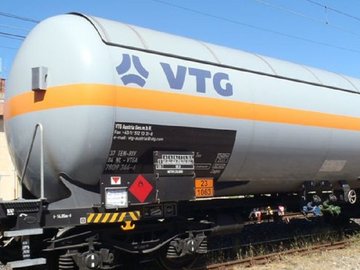 White liquid gas tank car with orange stripe and blue logo.