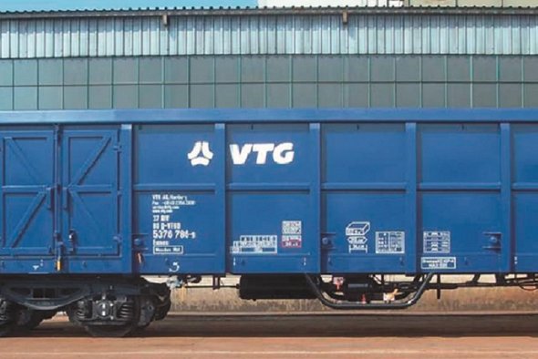 Blue VTG box wagon in front of gray building.