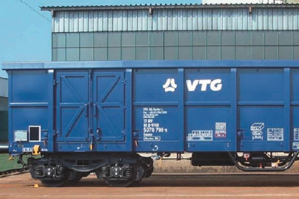 Blue VTG box wagon in front of gray building.