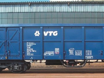 Blue VTG box wagon in front of gray building.