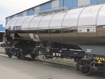 Silver chemical tank car with blue VTG logo in front of a hall.