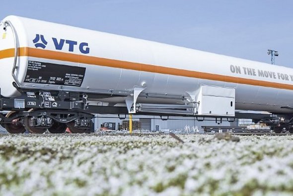 White liquid gas tank car with orange stripe and blue logo.