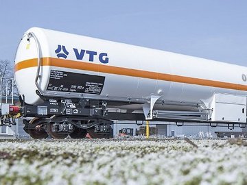 White liquid gas tank car with orange stripe and blue logo.