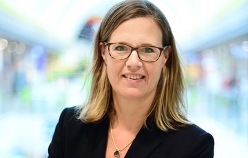 Blonde woman with glasses and black blazer