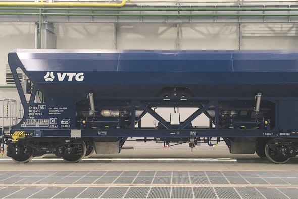 Blue hopper car with white VTG logo stands in a hall.