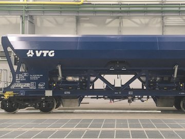 Blue hopper car with white VTG logo stands in a hall.